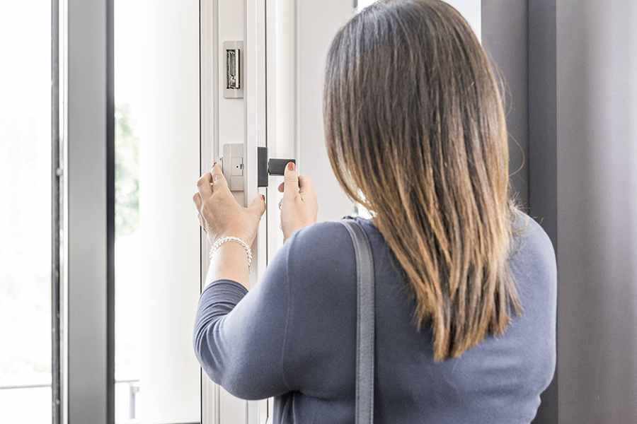 donna di spalle che controlla maniglia e ferramenta serramento